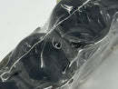 Black object wrapped in clear plastic on a light gray background